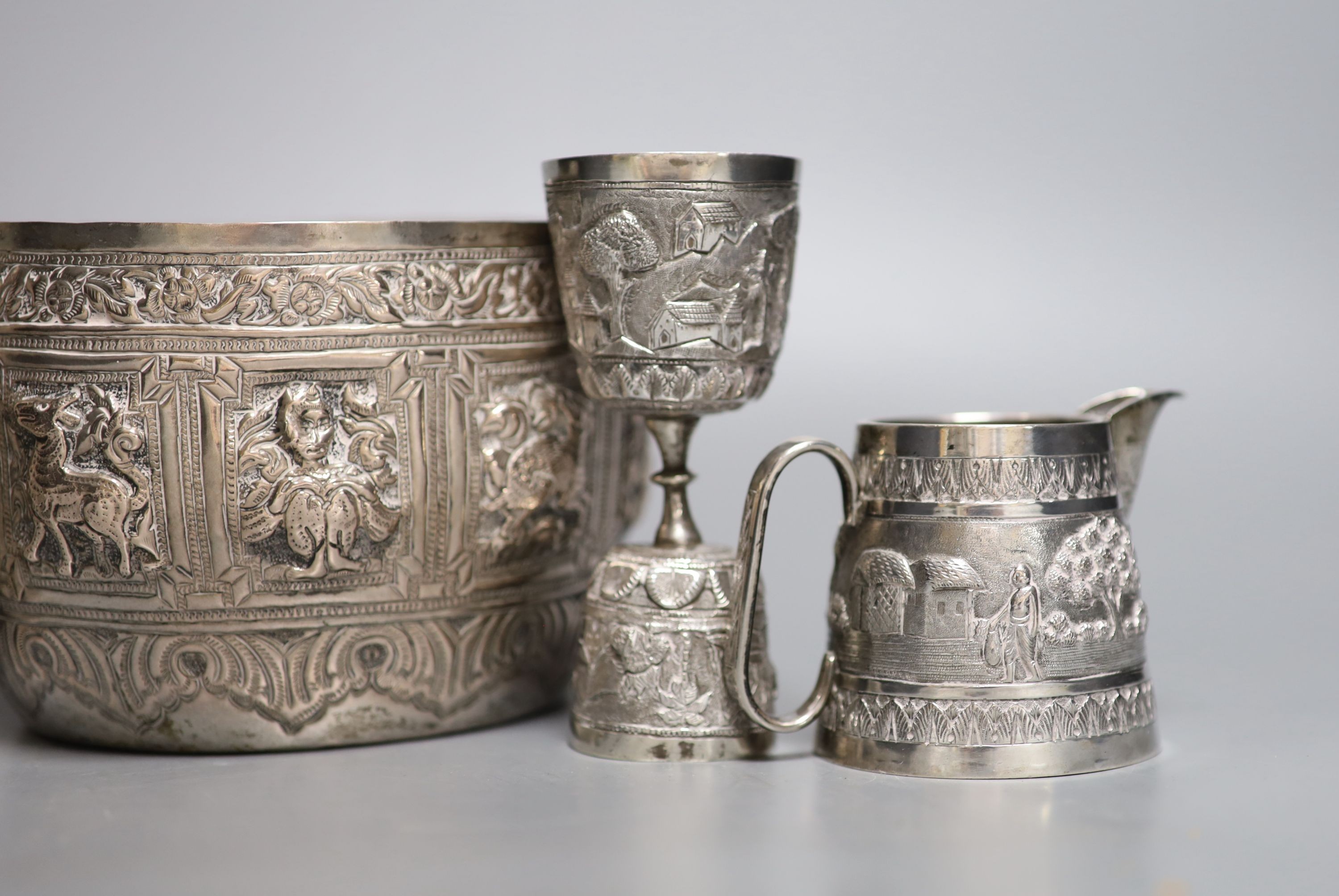 A group of Indian items including a white metal bowl embossed with animals, diameter 14.2cm, cream jug, measure, bowl, dish and beaker.
